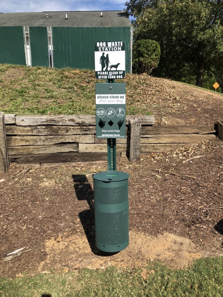 A green parking meter with a sign on it.